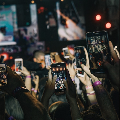 Scene of hands taking photos with cellphones of a concert