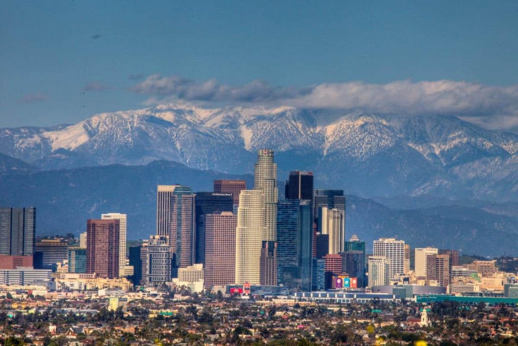 Los Angeles skyline during daytime overlooking snowy peaked mountains