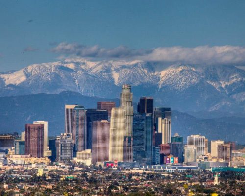 Los Angeles skyline during daytime overlooking snowy peaked mountains